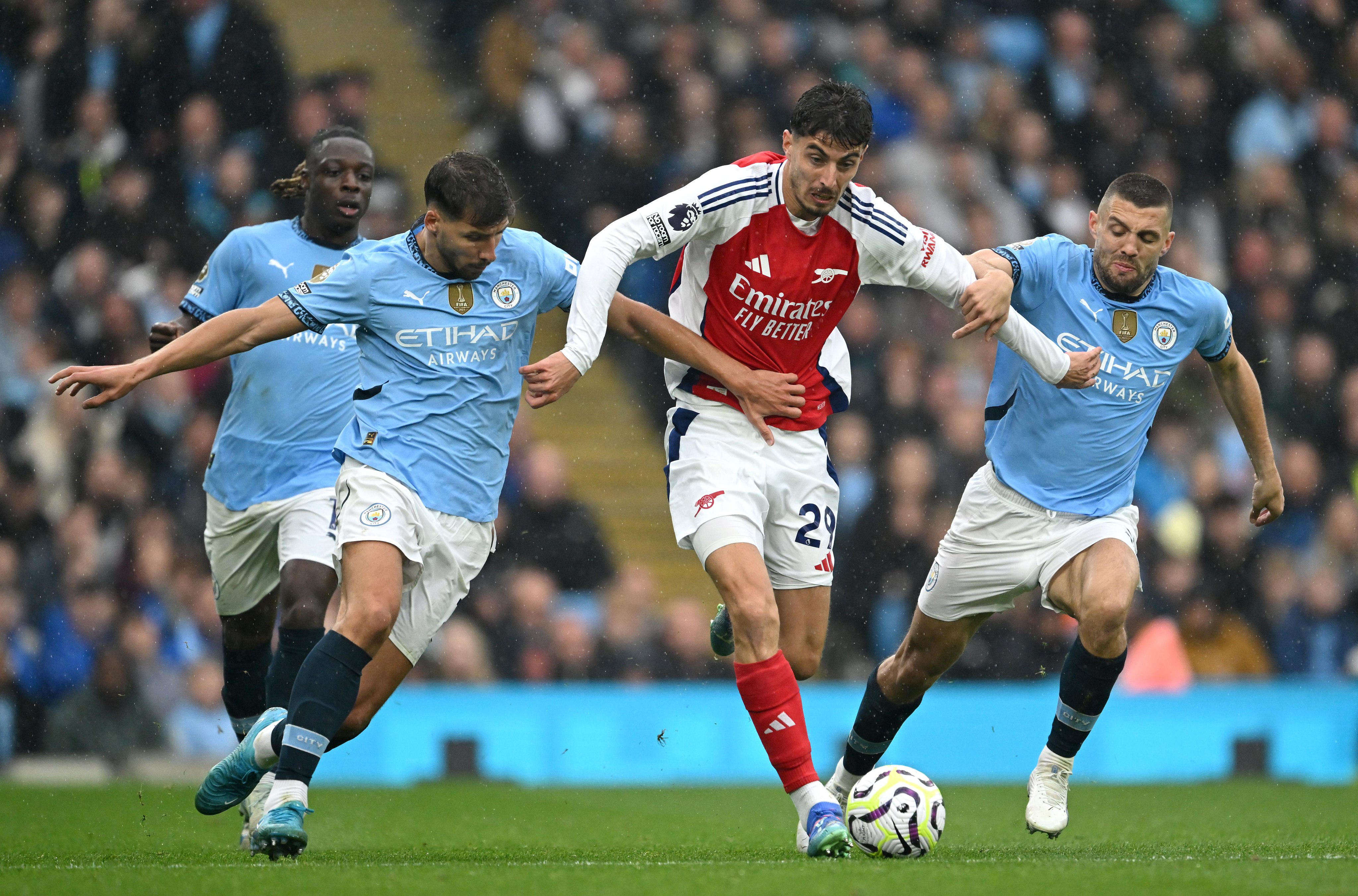 Kai Havertz holds off a couple of Man City players.