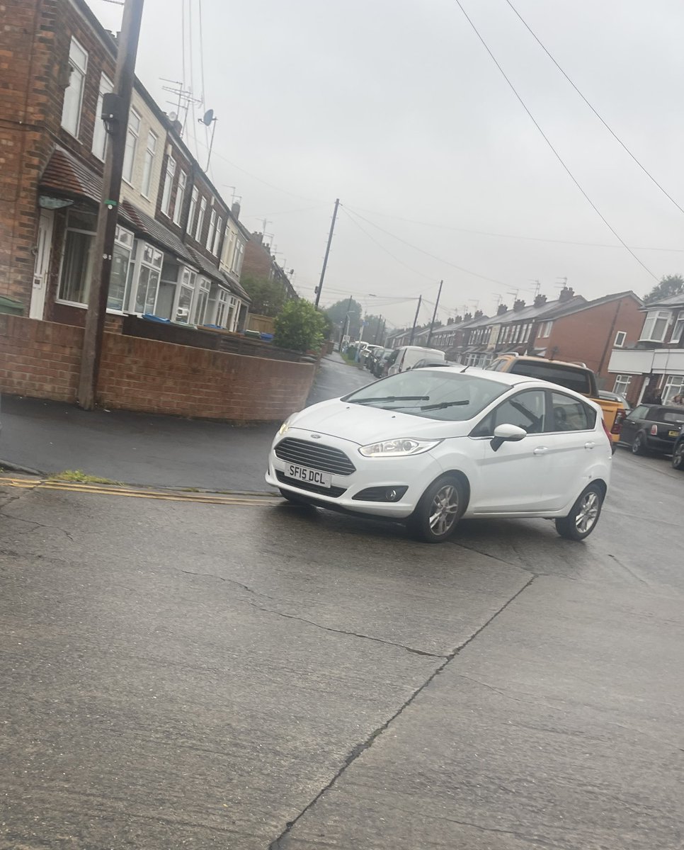 dgarnett's tweet photo. Another day. This time in the wet weather. More cars. Flying down dodging badly parked cars and kids. Woman in white car engine running playing on her phone while blocking drop curb for crossing. https://t.co/h2OCT9KCPl