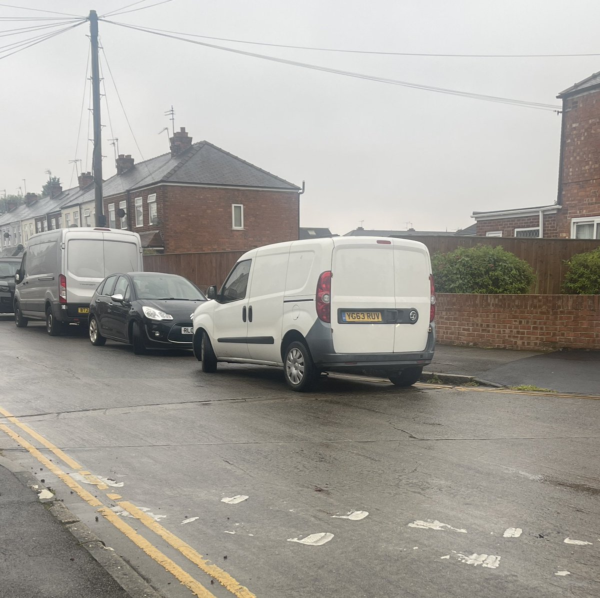 dgarnett's tweet photo. Another day. This time in the wet weather. More cars. Flying down dodging badly parked cars and kids. Woman in white car engine running playing on her phone while blocking drop curb for crossing. https://t.co/h2OCT9KCPl