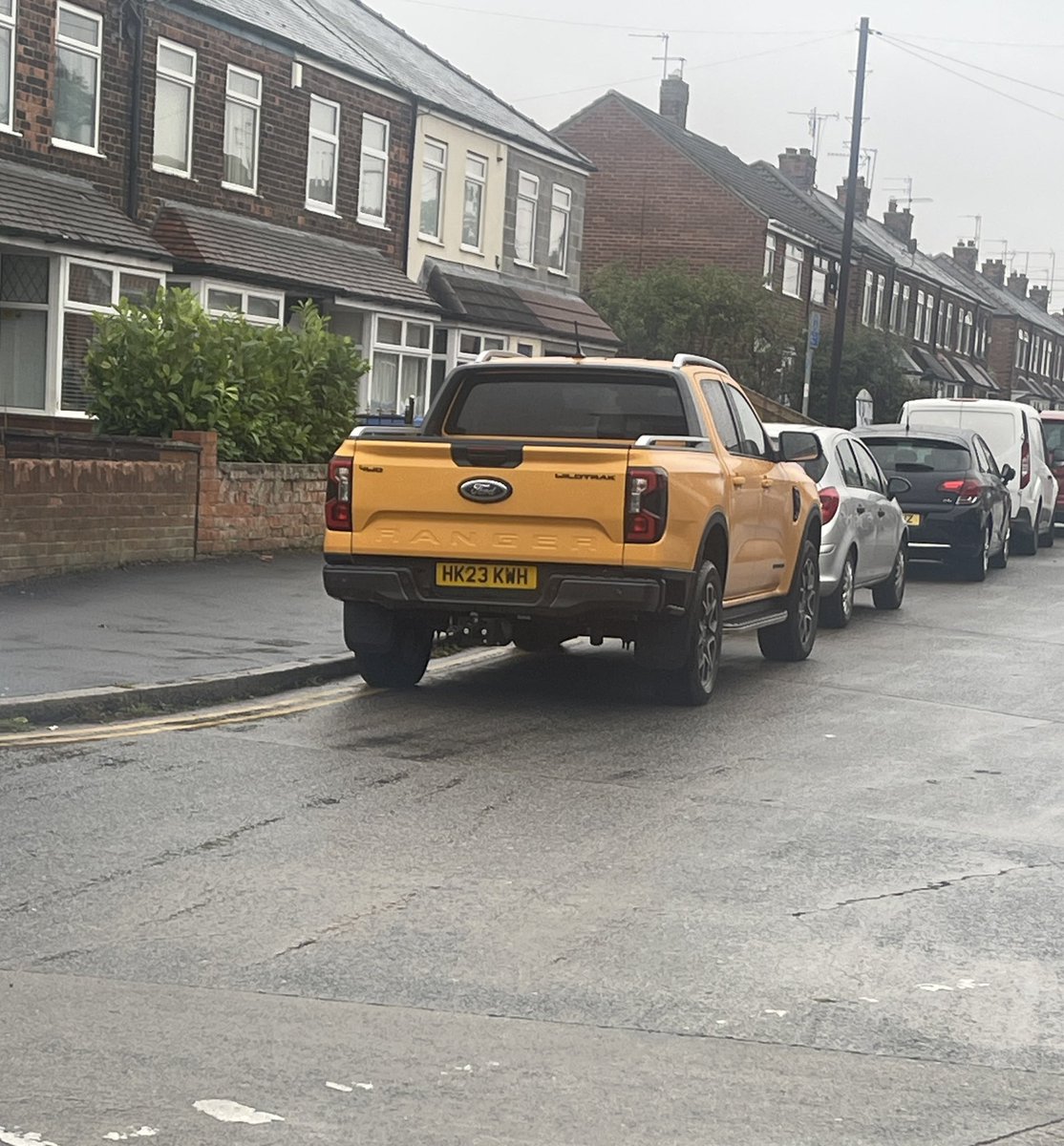 dgarnett's tweet photo. Another day. This time in the wet weather. More cars. Flying down dodging badly parked cars and kids. Woman in white car engine running playing on her phone while blocking drop curb for crossing. https://t.co/h2OCT9KCPl