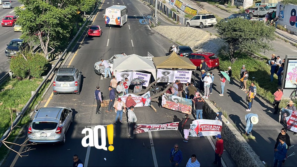 AlertaQro's tweet photo. #AlertaSucesos | 🚨🚨Autoridades liberan un carril a la circulación en el Boulevard Bernardo Quintana, a la altura de Las Américas. Los manifestantes aún mantienen dos carriles bloqueados en dirección a Paseo 5 de Febrero.

Las personas piden que se resuelva a su favor un litigio que tiene muchos años en el que exigen un pago porque dicen que el Boulevard Bernardo Quintana fue construido en tierras de su ejido.