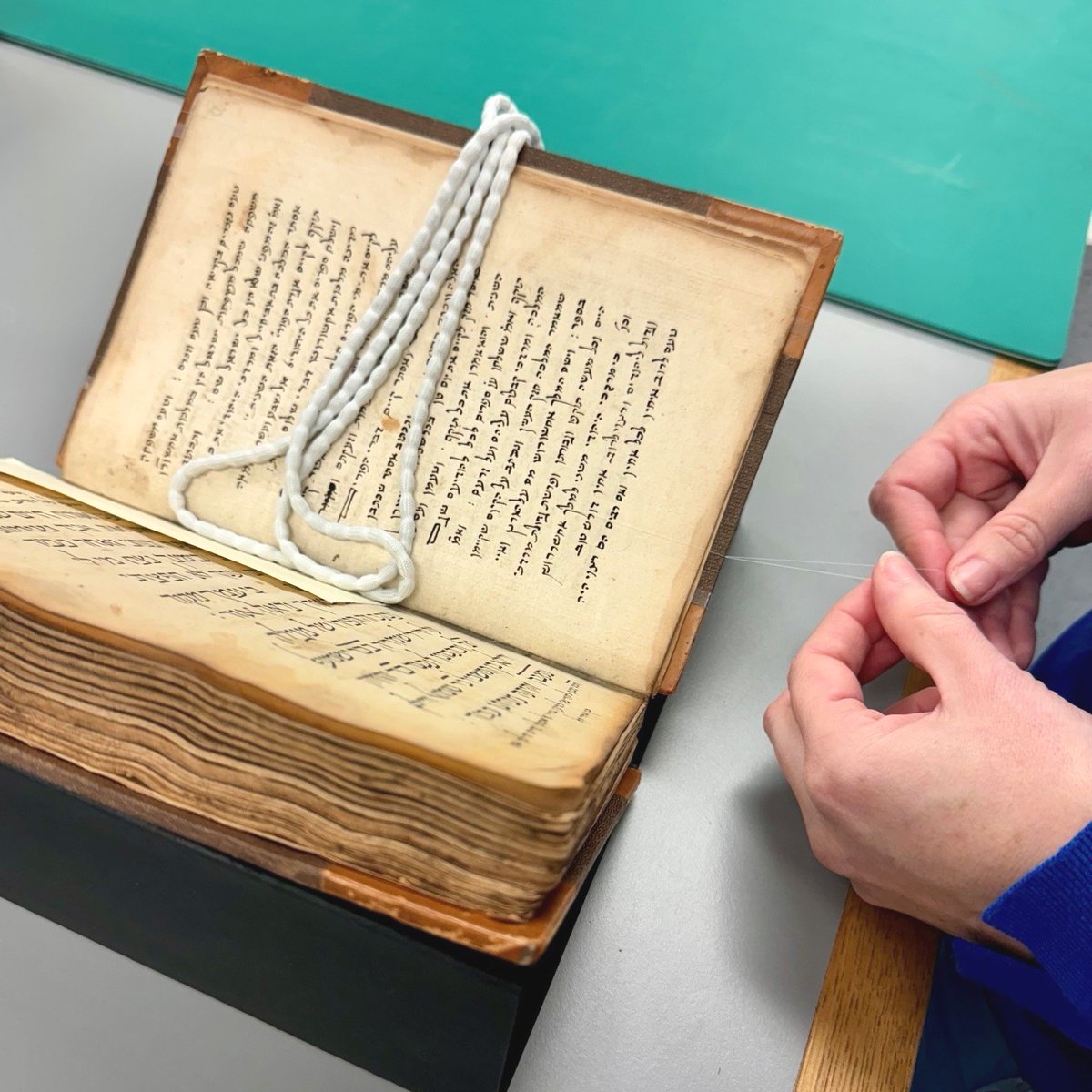 theUL's tweet photo. The #CULconservation team is preparing objects for our Endless Stories exhibition. Manuscripts are placed on a bespoke cradle and held in place with fine hair silk to keep them safe without obstructing the page!
#EndlessStories #ExhibitionInstallation #BookConservation https://t.co/WXFhgCVmMU