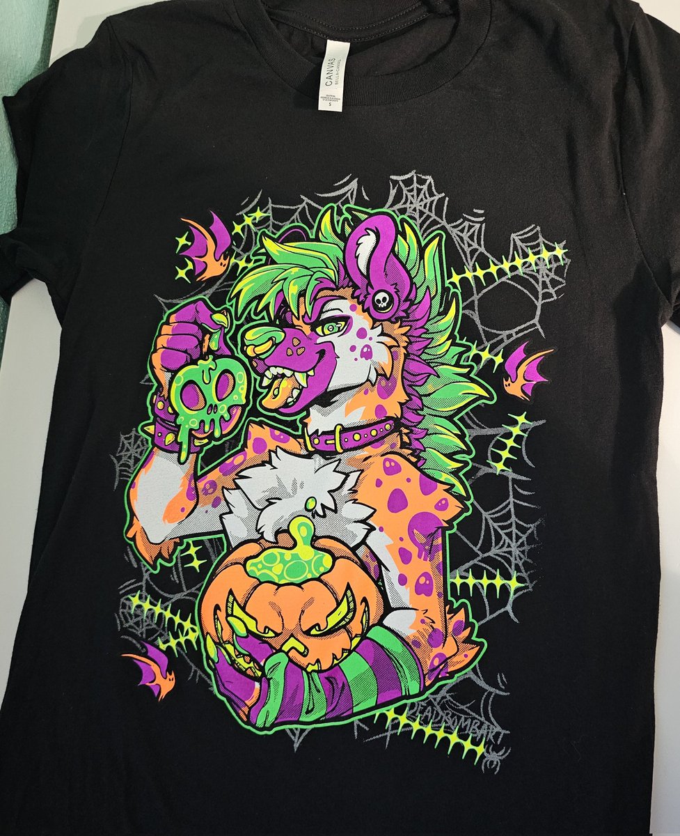 DeadBombArt's tweet photo. The Halloween yeens are almost ready!

I finally have a print of the ACTUAL colors ready to show off.
✨️Very blacklight, much wow UwU✨️

I plan on dropping them this Friday~
In standard, tanks, AND long-sleev
👀🧡💜💚 https://t.co/OAHVx4MPP0