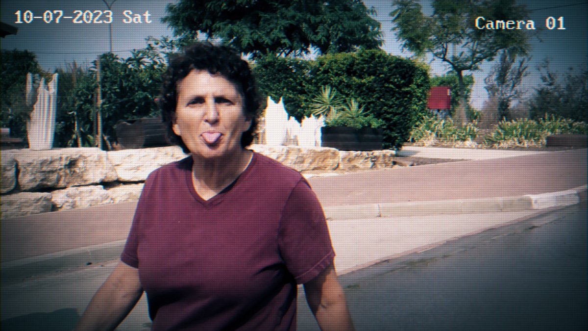 התאריך בפינה השמאלית של התמונה הזאת נותן רק רמז קלוש לסיטואציה המטורפת שמאחוריה: 7 באוקטובר, כבר שעת צהריים, אבל מחבלי הנוח'בה עדיין שולטים בקיבוץ בארי, עושים בו כבשלהם. רוצחים, חוטפים, שורפים. ובתוך כל התופת, זוהי כנרת גת. בת 69, עומדת מול מחבל מאיים, שרוצה לקחת אותה איתו, והיא