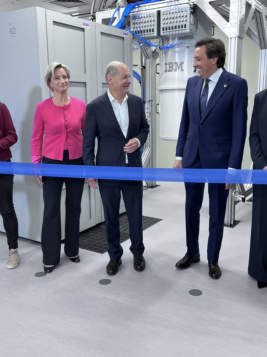 dcinsiderde's tweet image. Kanzler Olaf Scholz steht vor dem blauen Band, das durchschnitten gehört, um das erste #Quantencomputing #Rechenzentrum der @IBM außerhalb der USA in Betrieb zu nehmen. Hinter ihm werkelt ein „Eagel“.