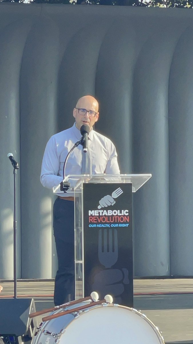DoctorTro's tweet photo. My speech from @MetRevolution 

The CDC recommends that people with diabetes get 50% of their calories from carbohydrates. Meanwhile, the American Academy of Pediatrics (AAP) advises that children with obesity should not be denied access to bariatric surgery or hormone injections. Yet, when it comes to lowering carbohydrates in adolescents, they mandate an extensive regimen of 20 lab tests and imaging studies.

I stand before you today not just as a physician, but as someone who has personally lived through the devastating consequences of a broken medical system… a system that has failed me, failed my family, and continues to fail millions of people every single day.

It’s time to face the facts: we are in the midst of a metabolic health crisis, and the very institutions that claim to protect our health are part of the problem.

At the age of eight, I was already on the path to obesity. By the time I became a young adult, I was burdened not just by my own weight, but by a medical system that offered nothing but empty advice. I watched as my family succumbed to diabetes, hypertension, and obesity. We went to Weight Watchers together, desperately seeking hope, while the real underlying issues were ignored. I ate the same school lunches full of processed junk and snacked on “convenient” and supposedly “healthy” foods like Lunchables.

I’ll never forget sitting in a cramped doctor’s office after waiting for hours… only to be placed on a scale and told that I was just like my family—fat. The advice I received? “Learn about calories.” But calories weren’t my issue. The real problem was understanding my hunger and the fact that I had been deprived of proper nutrition from day one.

The weight piled on until I became a 350-pound physician. My wake-up call didn’t come from the medical community, but from my own wife. She asked me to dig deep and find the solution, as I had done for everything else in medicine. So, I embarked on a ten-year mission to heal. I read 300 diet books by experts like Dr. Lustig, Dr. Teicholz, and Dr. Westman, and I pored over thousands of original research papers, trying to make sense of the USDA guidelines and the absurd recommendations from our so-called medical authorities.

What did I discover? I found that the advice to eat more starches, grains, and carbohydrates was a complete lie… not supported by the literature, not grounded in reality. These were outright lies.

At that point, I had never even cooked a steak in my life. I had no vested interest. I just wanted to heal… and I did. I lost 150 pounds, and I’ve kept it off for the last ten years with little effort. Not because of the nonsense in our dietary guidelines, but because I finally understood what true nutrition looks like.

Our experts have failed us. They continue to fail us. And it’s not just a failure of knowledge… it’s a failure of integrity.

I didn’t watch my family suffer only to sell out to pharma, supplement companies, or some veggie greens CEO. I’ve dedicated my life to exposing this failure. I’ve published ten papers. I’ve trained medical students, doctors, and coaches to understand the truth about metabolic health.

Seven years ago, I founded a nationwide telemedicine practice that has helped over 2,000 people lose nearly 100,000 pounds. Today, we partner with large companies to provide metabolic health services free to their employees. And it’s working. Manufacturing workers, truckers, fencing contractors, and lumber yard workers are all achieving incredible results… not because of a magic pill, but because we’re giving them the truth about metabolic health.

I’m honored to be here today, but let me be clear: honor alone won’t solve this problem. We need action. That’s why I serve on the board of the @TheSMHP … to ensure the next generation of doctors doesn’t remain as blind as mine was

My personal mission, and the mission of my medical practice, is simple: to end metabolic disease.

Metabolic health is a birthright