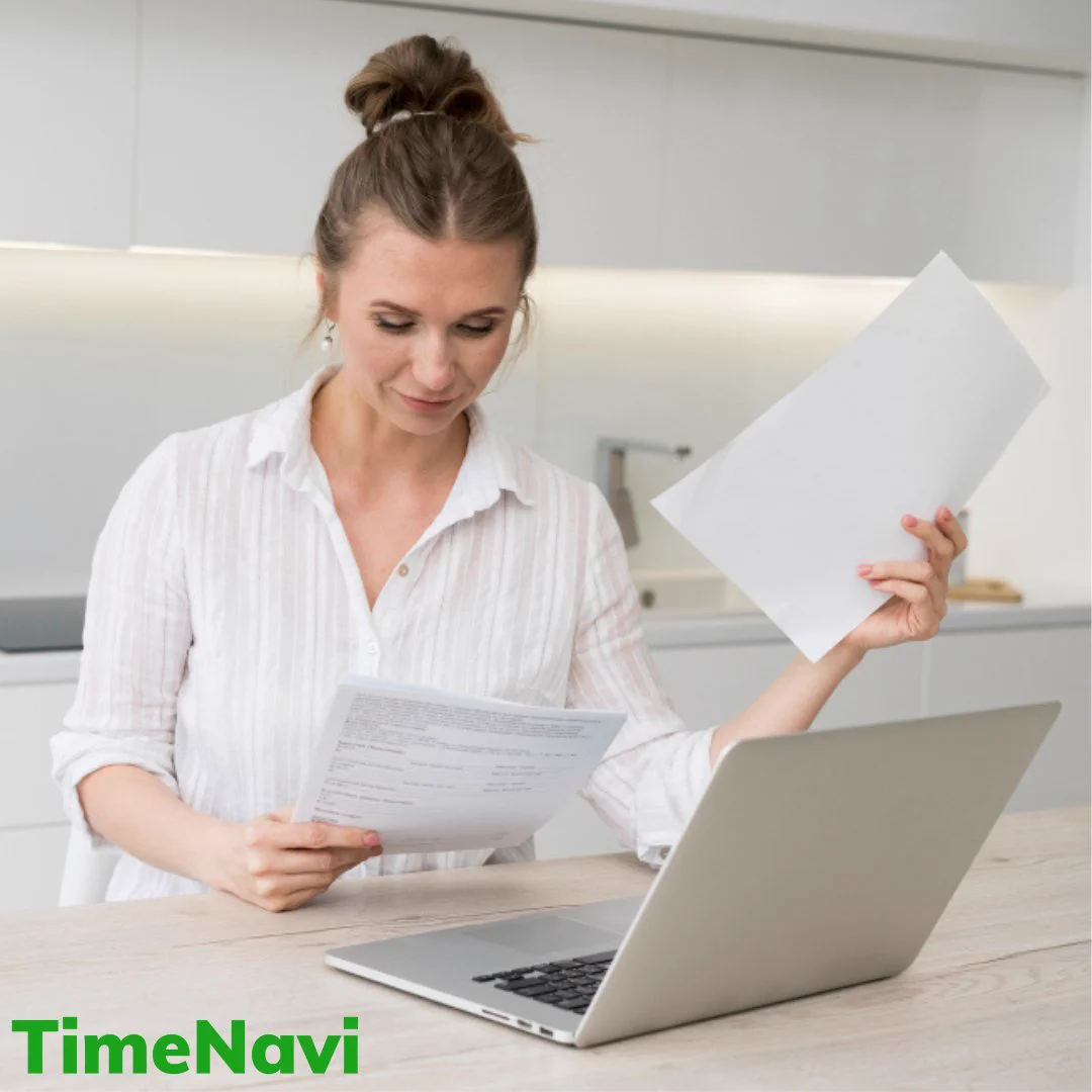 Person in a white shirt reviewing documents while working on a laptop in a modern kitchen, with the TimeNavi logo visible on the image.
