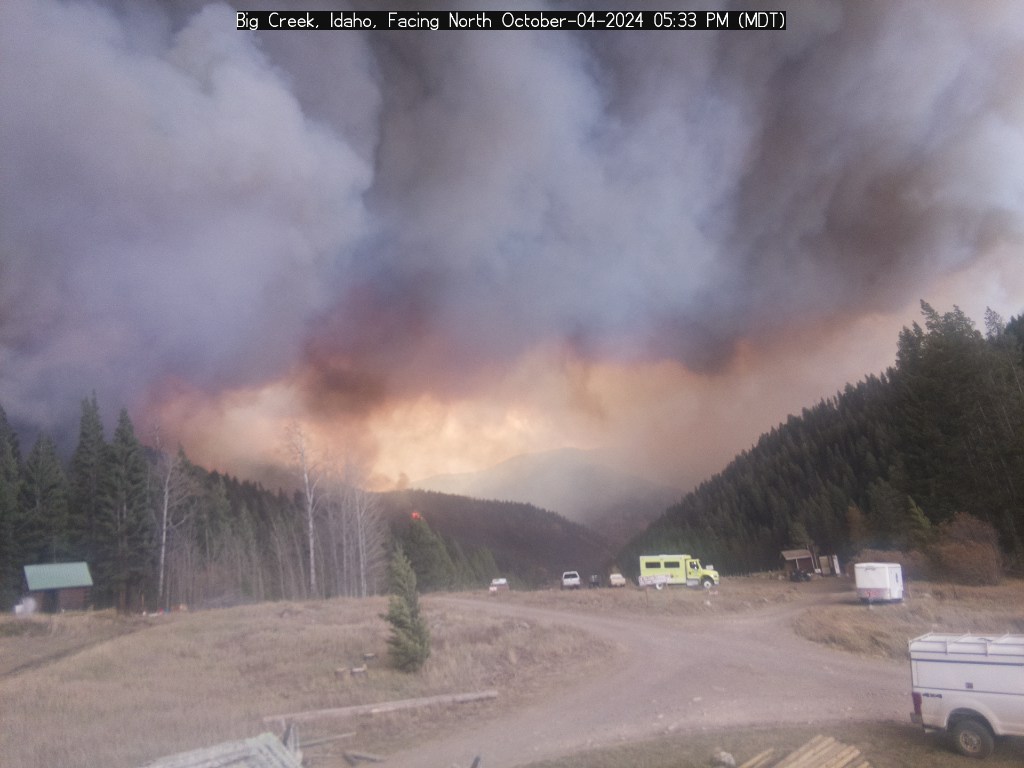 mn_storm's tweet photo. The Big Creek web camera has a clear view of spotting underneath the column of the #LoganFire. Note how the spotfire smoke and trees are tilted towards the fire, this is a sign of strong fire-generated inflow. Also, Big Creek lodge is under threat right now. #idwx #idfire https://t.co/vJiGmUvjxc
