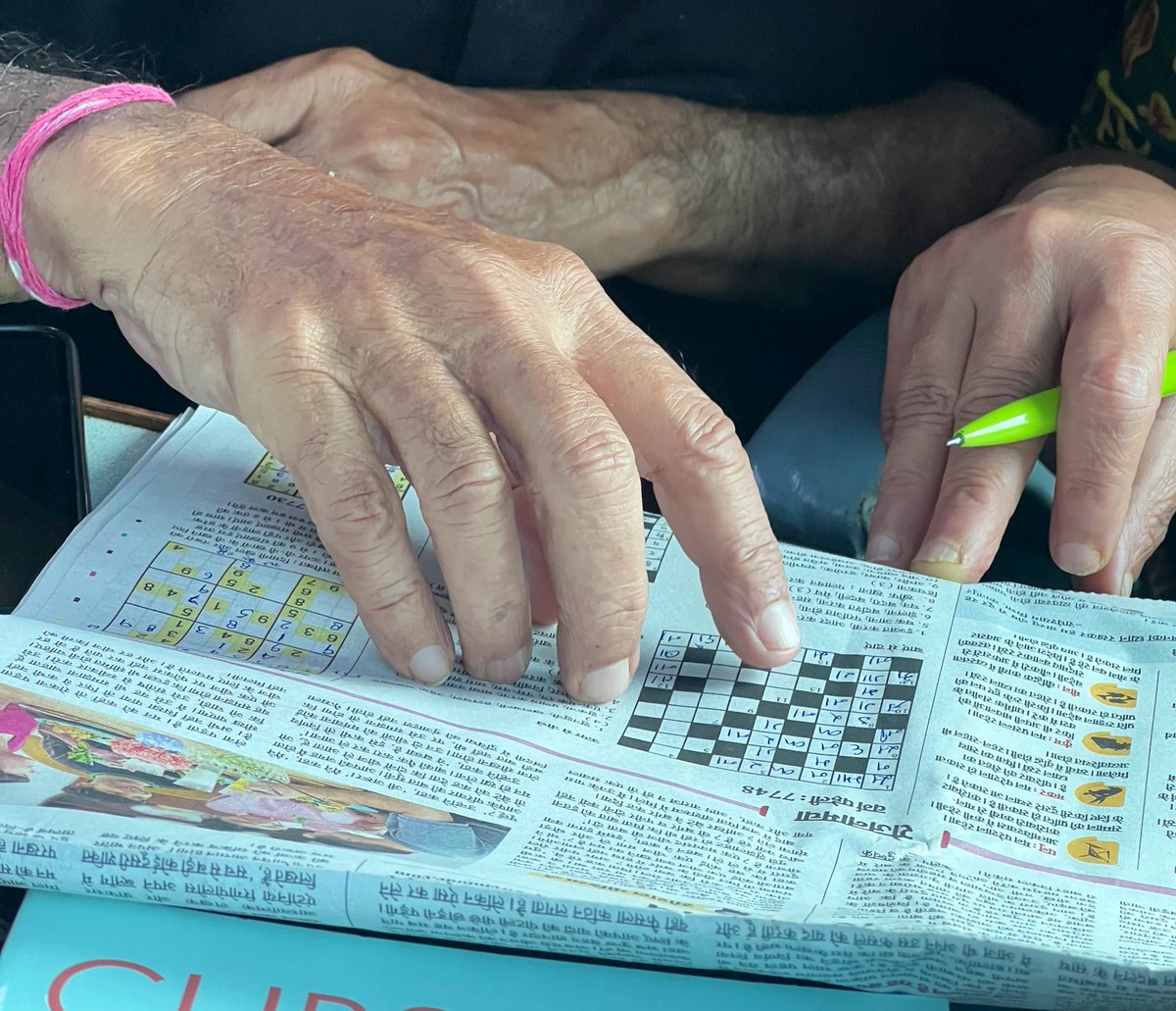 an old couple, in front of me, solving the crossword together.