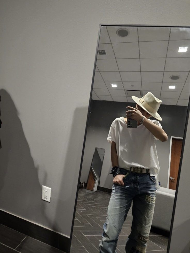 In this grey-walled room, I’m just vibing, playing music, and living it up. Rocking my casual fit with a cowboy hat to top it off, gotta say, I’m feeling good. There’s something about treating myself to this moment—it’s like, who wouldn’t be happy when you look this cool, right?