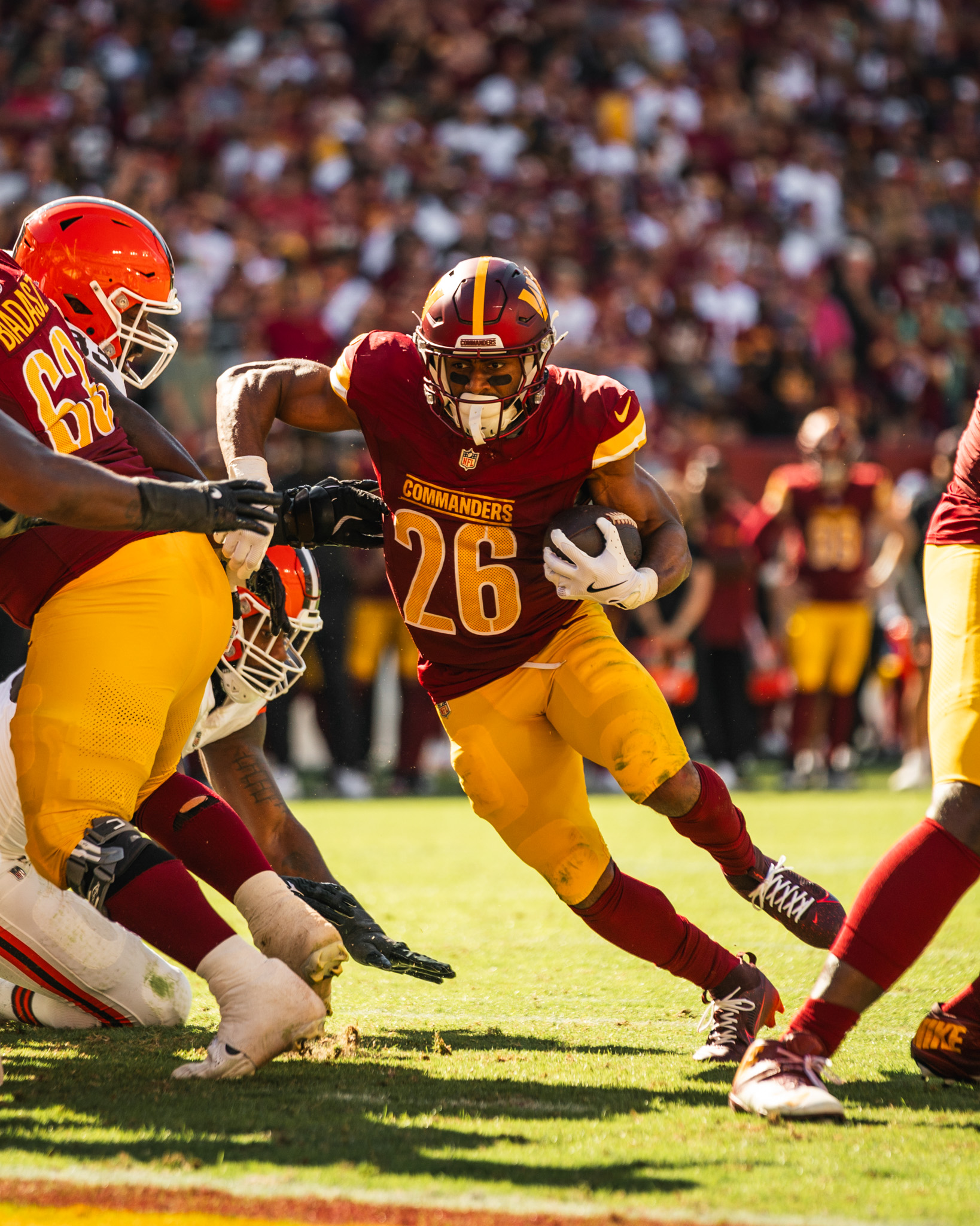 Photo of Jeremy McNichols running. He is holding a football in his right hand. He is wearing a burgundy helmet, burgundy jersey, gold pants, white football gloves and burgundy socks.