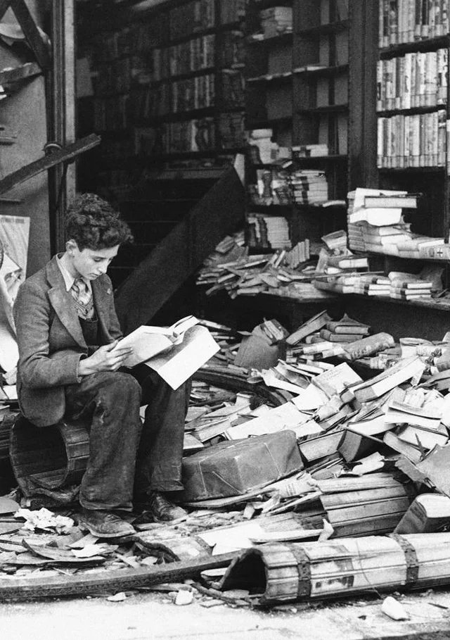 Amidst the ruins of a London bookshop, a boy sits and reads a book named “The History of London".
 October 8, 1940.