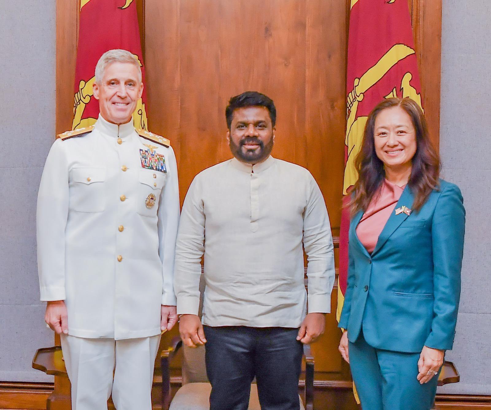 Admiral Koehler, Sri Lankan President Dissanayake, and Ambassador Chung stand and smile in front of flags.