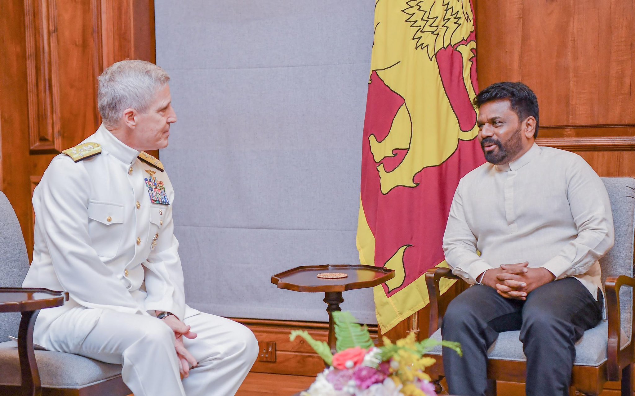 Admiral Koehler and Sri Lankan President Dissanayake sit and talk in front of flags.