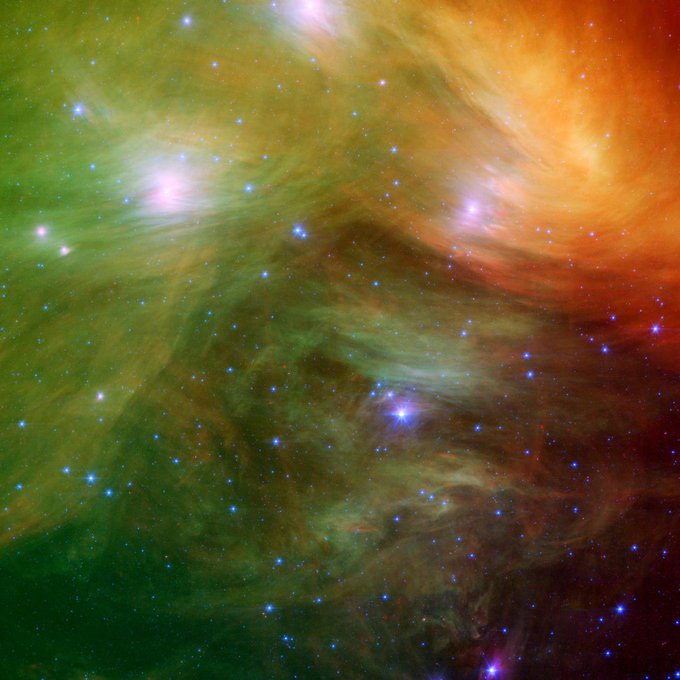 Clouds in shades of green and red streak across the image, surrounding many stars. Some of the stars are brighter than others. Credit: NASA/JPL-Caltech