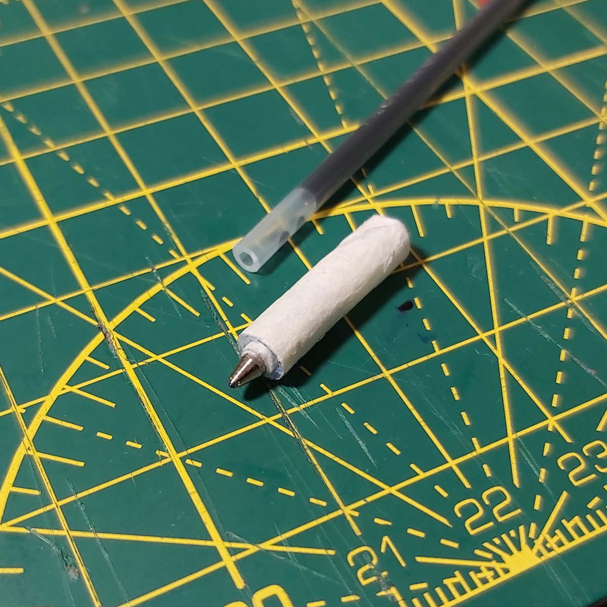benryves's tweet photo. I bought a cheap pack of gel pens, pulled the tip off one, wedged it into a piece of plastic tube from a bottle of bleach spray and wrapped it in tape until it was roughly the right size. It... almost works? It's definitely trying, even if the lumpy thing jams the carriage. https://t.co/waBJhGromL