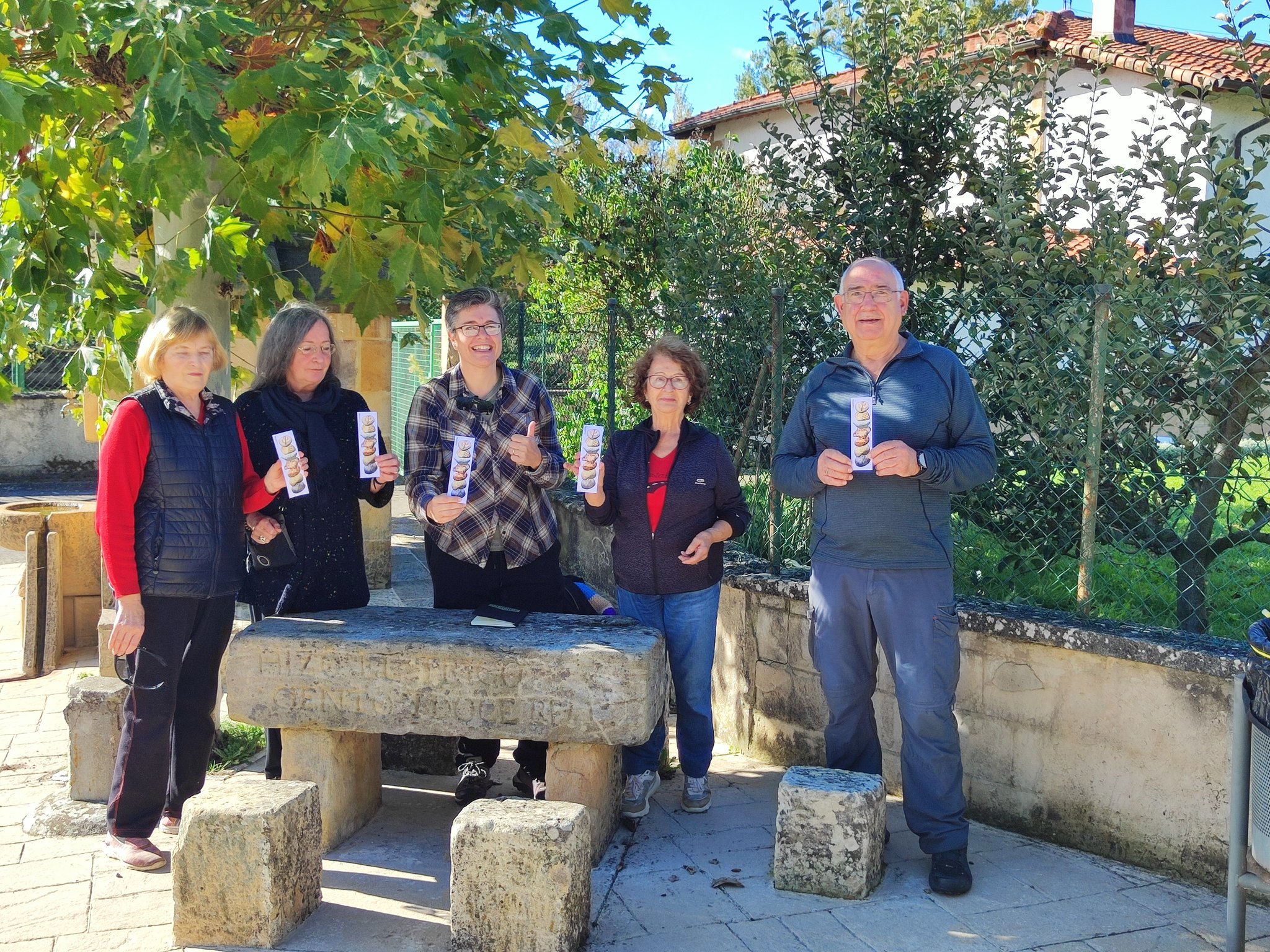 Imagen de cinco personas junto a una mesa y bancos de piedra.