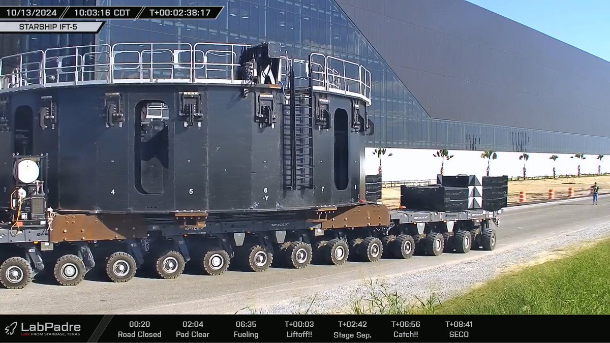 Après le rattrapage incroyable, le booster 12 est en cours de descente par les bras de Mechazilla et le stand permettant de le transporter est en route pour le pas de tir.