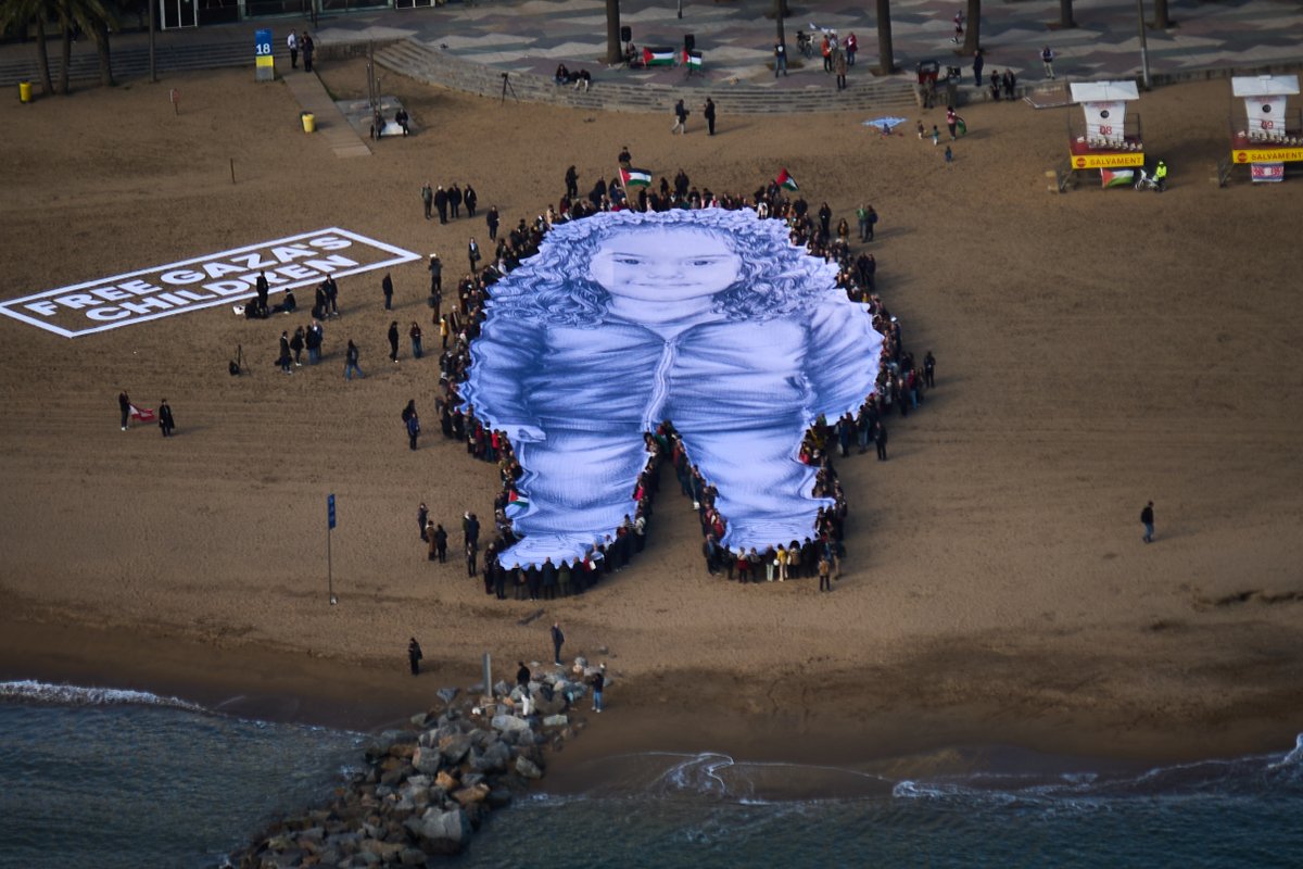 gulftoday's tweet image. People hold a giant portrait of Hind Rajab, a five-year-old Palestinian girl who was killed during the war in Gaza, on a beach in Barcelona, Spain, on Thursday. #GazaCeasefire 
gulftoday.ae