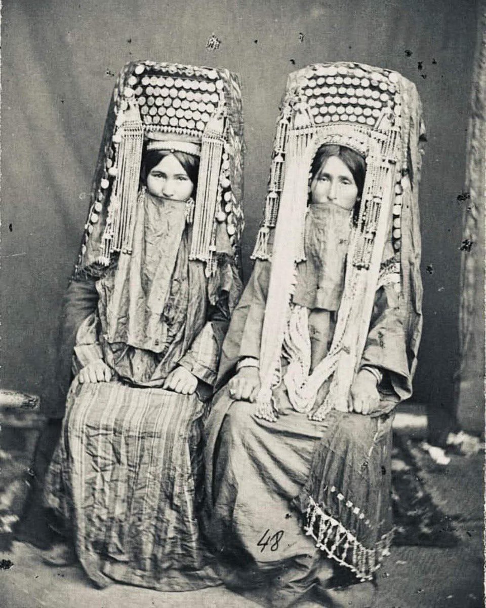 Dr_TheHistories's tweet photo. The women in this photograph belong to the Yomut (Yomud) Turkmen—one of the major tribal groups of the Turkmen people—photographed in 1883 near Krasnovodsk, during the final decades of Russian imperial expansion into Central Asia. This was a moment of immense upheaval, when nomadic and semi-nomadic cultures were being documented, regulated, and slowly forced into colonial frameworks that did not reflect their social realities.

Yomut women lived within a pastoral, clan-based society where women’s roles were far more economically and socially significant than many outsiders assumed. They managed households that were also production centers—spinning, weaving, embroidery, felt-making, and textile production were not “domestic hobbies,” but essential economic labor. Yomut carpets, bags, and textiles were traded across vast regions, and women controlled much of this craft knowledge. Their work carried tribal identity, history, and status woven directly into pattern and color.

The clothing in this image is not ornamental excess—it is biography. The towering headdresses (often called gupba or regional variants) and heavy silver adornments signaled marital status, tribal affiliation, family wealth, and protection. Silver was believed to guard against illness and evil spirits, especially for women, whose bodies were seen as powerful and vulnerable thresholds. Coins sewn into garments were both adornment and portable wealth—women literally wore their economic security.

Marriage among the Yomut was negotiated within tribal systems that valued alliances, bridewealth, and fertility, but women were not invisible within these arrangements. Older women, especially mothers-in-law and elder matriarchs, held significant authority inside extended families. Oral tradition, genealogy, and cultural memory were passed primarily through women, making them the custodians of identity in a society without written archives.

This photograph also reflects the colonial gaze. Russian ethnographers often framed Turkmen women as “exotic,” static, or oppressed, freezing them in images meant for imperial catalogs. What the photograph cannot show is movement—women riding horses, managing camps, surviving droughts, war, and forced resettlement. Nor does it show how these women would soon face imposed borders, sedentarization, and the erosion of tribal autonomy under Russian and later Soviet rule.

#drthehistories