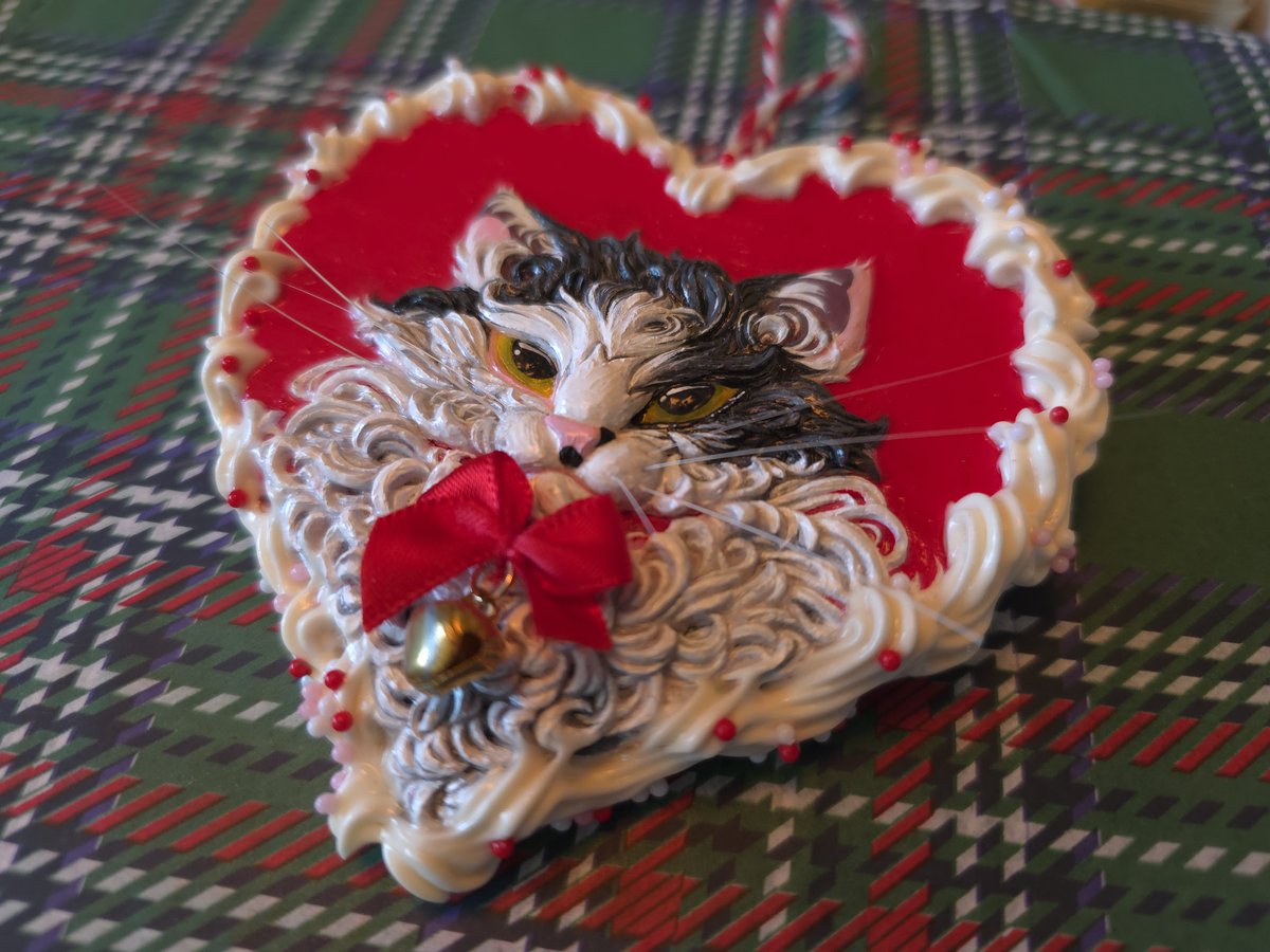 An ornament of my kitty made with her shed whiskers, polymer clay sculpted over wood, air dry clay, fake sprinkles, an earring, and lotsa love 💕