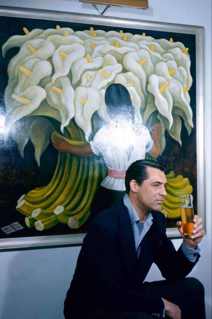 TheCinesthetic's tweet image. Cary Grant drinking a beer in front of the painting "Flower Vendor" by Diego Rivera (1955).