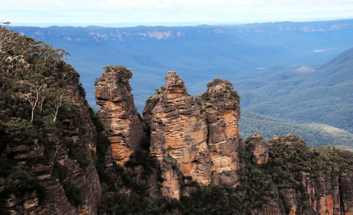 The Three Sisters, those famous rocks in Australia's Blue Mountains are iconic, dramatic, and unforgettable. Ready to stand on this edge of wonder near Sydney? JMart Travels can help you plan the perfect trip. #Australia #BlueMountains #ThreeSisters #WanderAustralia #TravelDreams