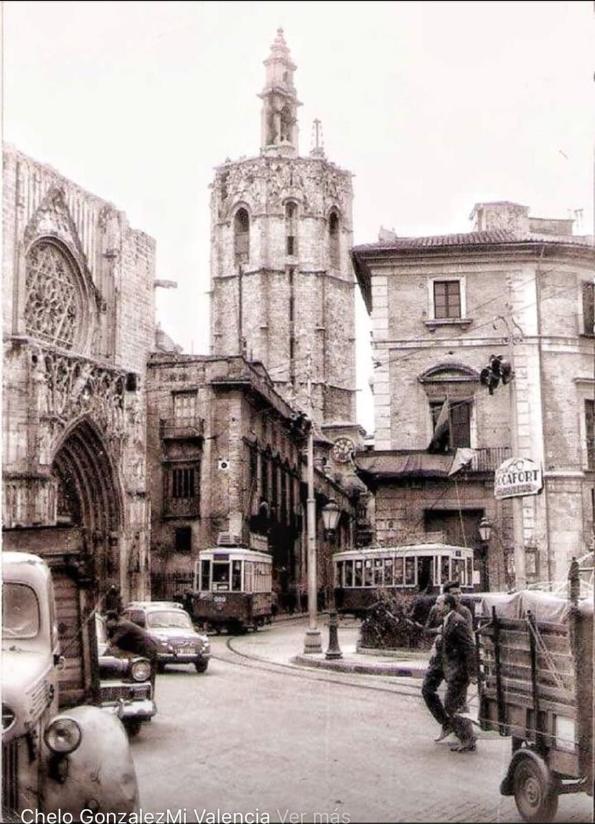 València, anys 1960. Tamvies, cotxes i vianants circulant per la plaça de la Mare de Déu i pel carrer Micalet.