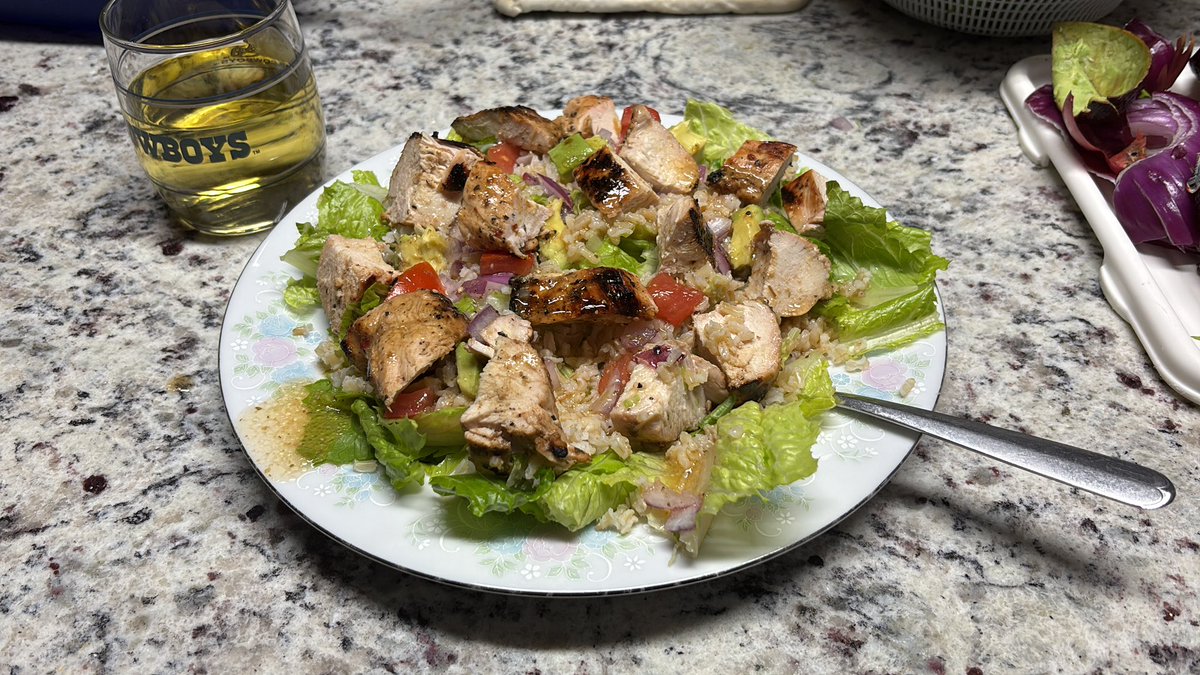 Eating healthy tonight. Grilled marinated garlic &amp; herb chicken, white rice, lettuce, tomato’s, avocado, chopped red onion, drizzled a three cheese Italian dressing. Topped off with a glass of a Woodbridge Chardonnay.