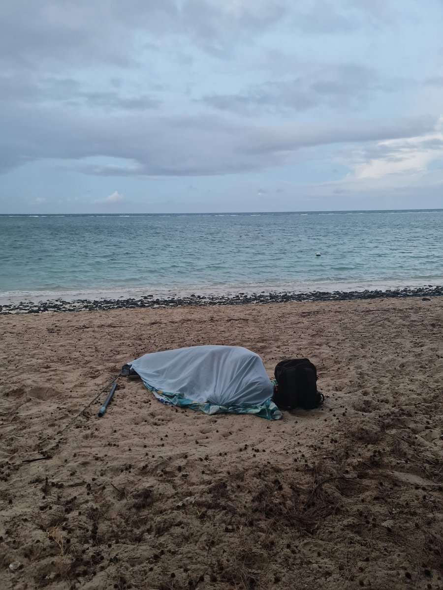 Saat 05:20.
Güneş yeni doğuyor; hava hâlâ ılık.
Plaj henüz sahne değil.
Kumun üzerinde, örtüsüne sarınmış bir beden uyuyor.
Oltalar ayağının dibinde, yanında sırt çantası.
Turistin günü başlamadan önce, yerel hayat çoktan başlamış oluyor.
Bu saatte plaj, gerçekten kamusal.