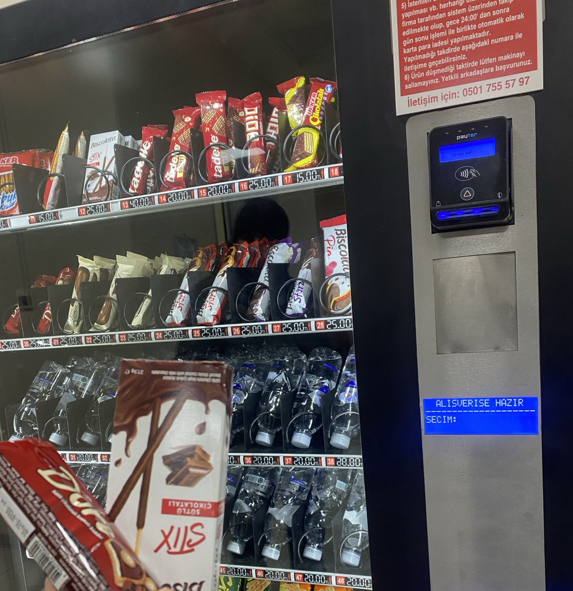 Bu otomat o kadar dandik ki asla bir ürün alamıyorsun çünkü düşmüyor, ucunda kalıyor. İkinci ürünü de birinci ürünü düşürmek için alıyorsun. Birinci ürünü düşürmek için aldığın ikinci ürünü de düşürmek için aynı anda makinaya yandan birisinin omuz atması gerekiyor. Dehayız…