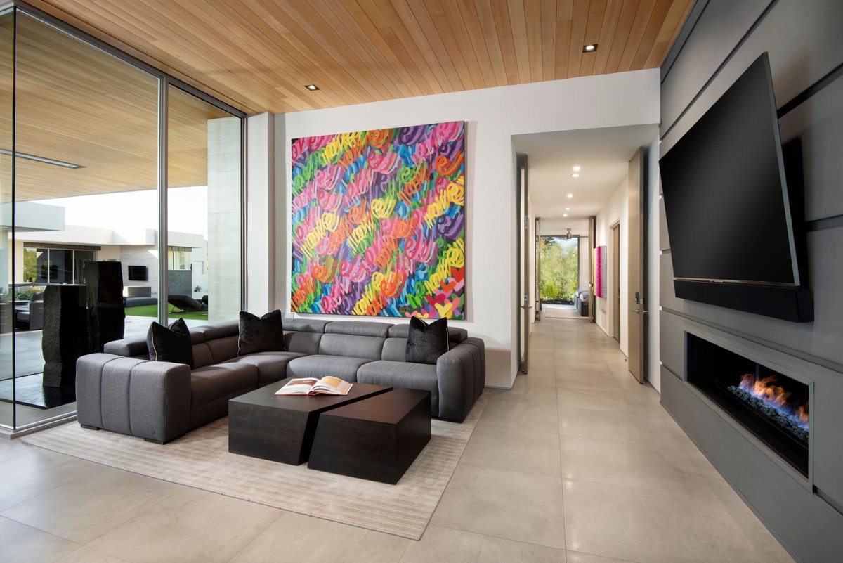 An intimate sitting area just outside the office and the hallway leading to the primary suite allows for private chats or some much-needed downtime. A low fireplace, big-screen TV and vibrant painting by Chris Riggs make the space a destination in itself.