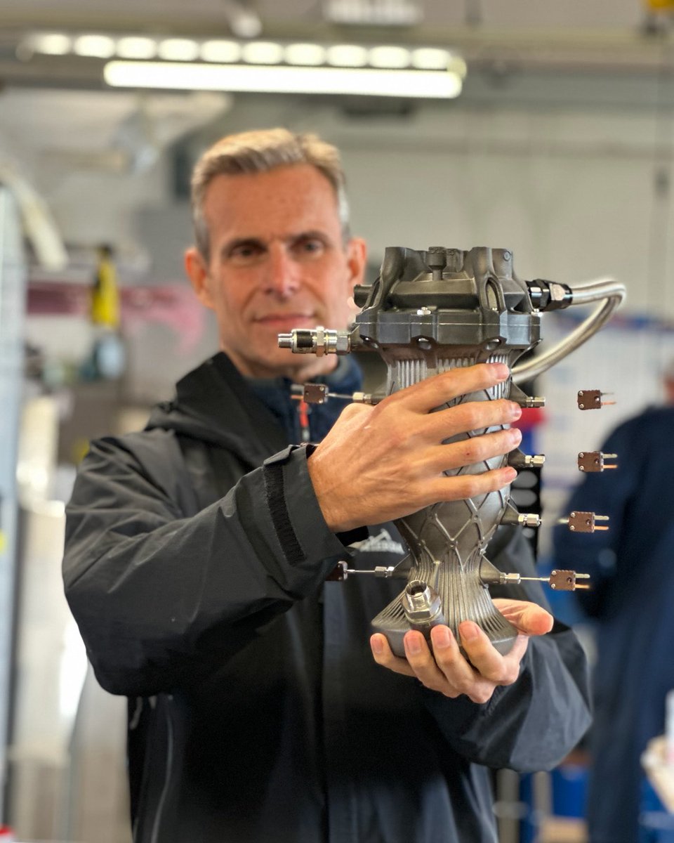 leap_71's tweet photo. LEAP 71 co-founder @linkayser holding a fully instrumented 6 kN KeroLOX thruster. This rocket engine was generated without human intervention by the Noyron Large Computational Engineering Model and printed in Inconel 718 using an @HBD_Technology metal additive manufacturing system.
