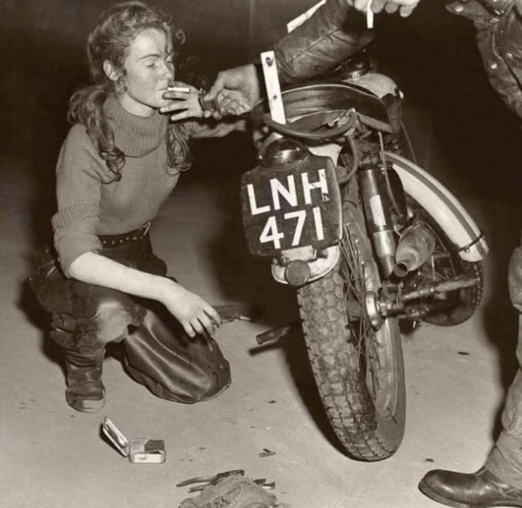 archeohistories's tweet photo. A ton-up girl fixing her Triumph, 1950s....

The photograph captures a small, electric moment in postwar Britain, a young woman kneeling beside her motorcycle, cigarette between her lips, wrench in hand. She was part of the “ton-up” subculture, a rebellious generation of riders who pushed their Triumphs and Nortons past the coveted “ton”—100 miles per hour. To them, speed was freedom, and the road was both escape and identity.

Her leather boots and rolled sleeves speak of a time when women on motorcycles were still an act of quiet defiance. The streets of London and Manchester echoed with the roar of engines and rock ’n’ roll, as the Café Racer scene grew around smoky roadside diners and midnight rides. These riders were dismissed as troublemakers by many, but they were pioneers of a youth movement that celebrated independence, style, and risk.

The term “ton-up girl” was rare but real, women like her helped redefine gender expectations in the 1950s, paving the way for the later Mods and Rockers movements that shaped Britain’s cultural identity.

© British History Unveiled

#archaeohistories