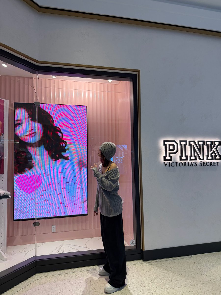Momo taking pics infront of a VS store with her ads playing and
