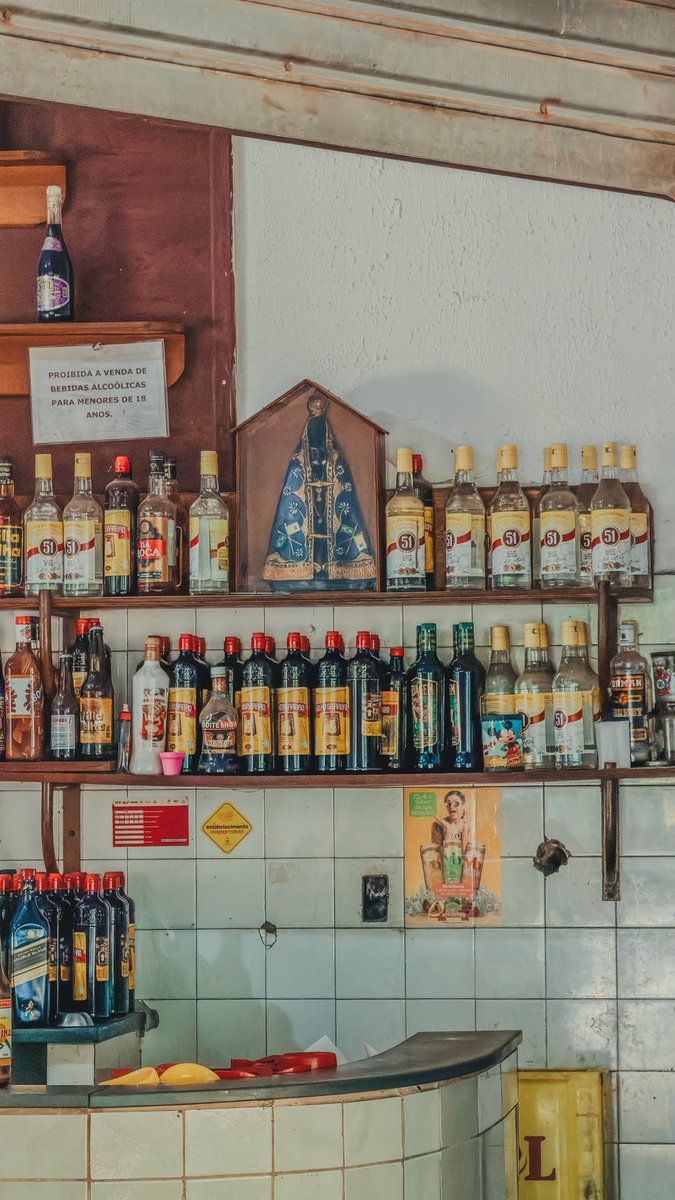 LeviKaique's tweet image. Isso aqui é muito Brasil. Uma imagem de Nossa Senhora Aparecida em um boteco cercada por pinga kk