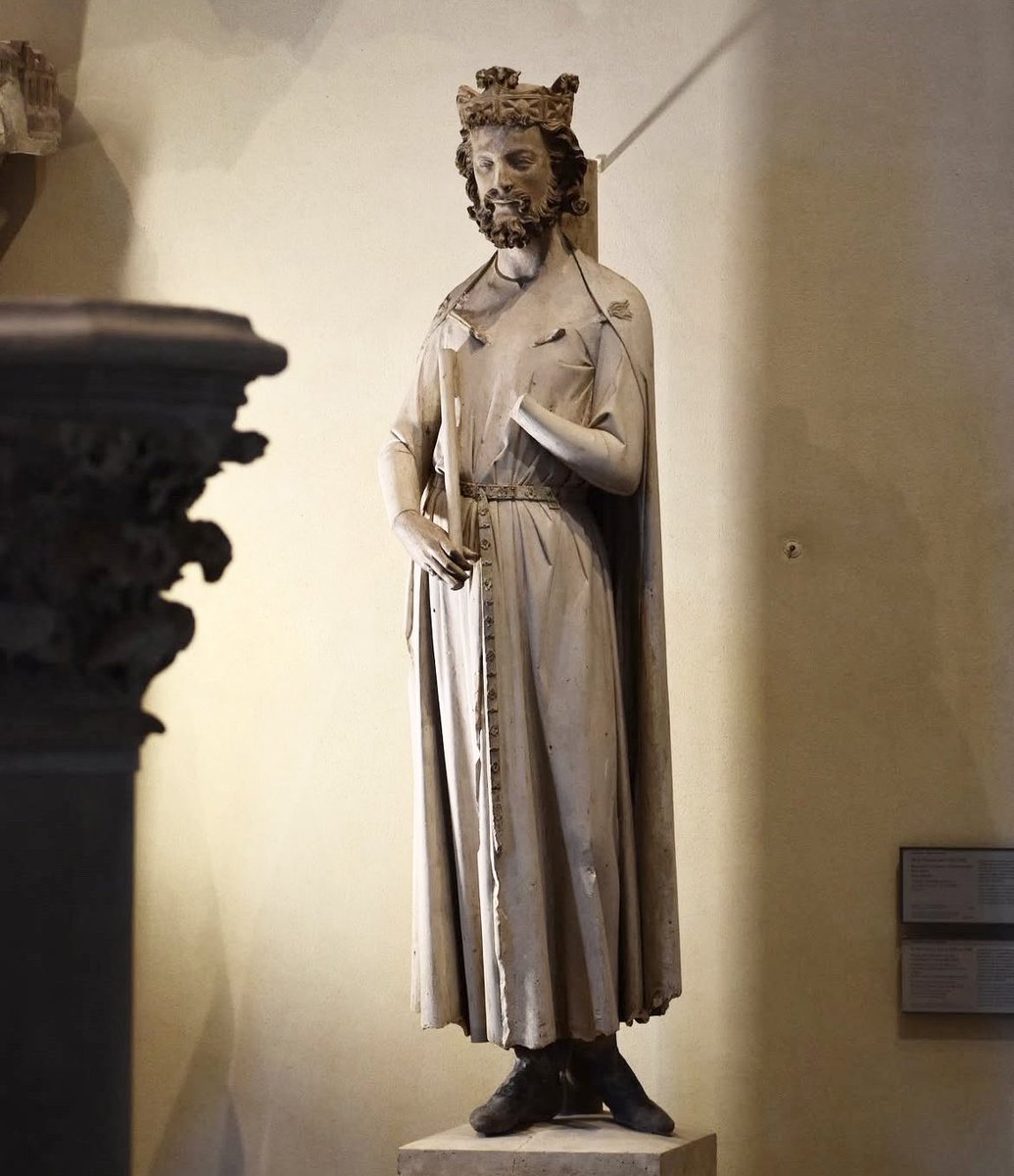 MuseeLouvre's tweet photo. #UnJourUneOeuvre/#WorkOfTheDay
🇫🇷 Cette statue est une représentation du roi Childebert Ier, fils de Clovis, fondateur de l'abbaye Sainte-Croix-Saint-Vincent au 6e siècle, devenue plus tard Saint-Germain-des-Prés. C’est un portrait dit rétrospectif, car réalisé au 13e siècle.
Le roi est vêtu d'une robe serrée à la taille par une ceinture de cuir à ornements métalliques. Il portait dans la main droite un sceptre aujourd'hui mutilé tandis que la main gauche retenait la bride d'un lourd manteau. Il est coiffé d'une couronne à quatre fleurons.
C'est un des exemples les plus précoces du nouveau style qui s'épanouit à Paris vers le milieu du 13e siècle. Après 1240, les sculpteurs acquièrent en effet plus de liberté dans le jeu des volumes. Une sorte de désinvolture dans la gestuelle s’installe. Le visage de Childebert, à la barbe et à la chevelure bouclées, est proche de celui du Christ du portail central de Notre-Dame de Paris.
∴
🌎 This statue is a representation of King Childebert I, son of Clovis and founder of the Sainte-Croix-Saint-Vincent abbey in the 6th century, which later became Saint-Germain-des-Prés. This is a retrospective portrait, as it was sculpted in the 13th century.
The king is wearing a robe cinched at the waist by a leather belt with metal ornaments. In his right hand, he carried a sceptre, now mutilated, while his left hand held the strap of a heavy cloak. He is wearing a crown with four fleurons.
This is one of the earliest examples of the new style that flourished in Paris around the middle of the 13th century. After 1240, sculptors acquired greater freedom in their use of volume. A kind of casualness in gestures took hold. Childebert's face, with its beard and curly hair, is similar to that of Christ in the central portal of Notre-Dame de Paris.