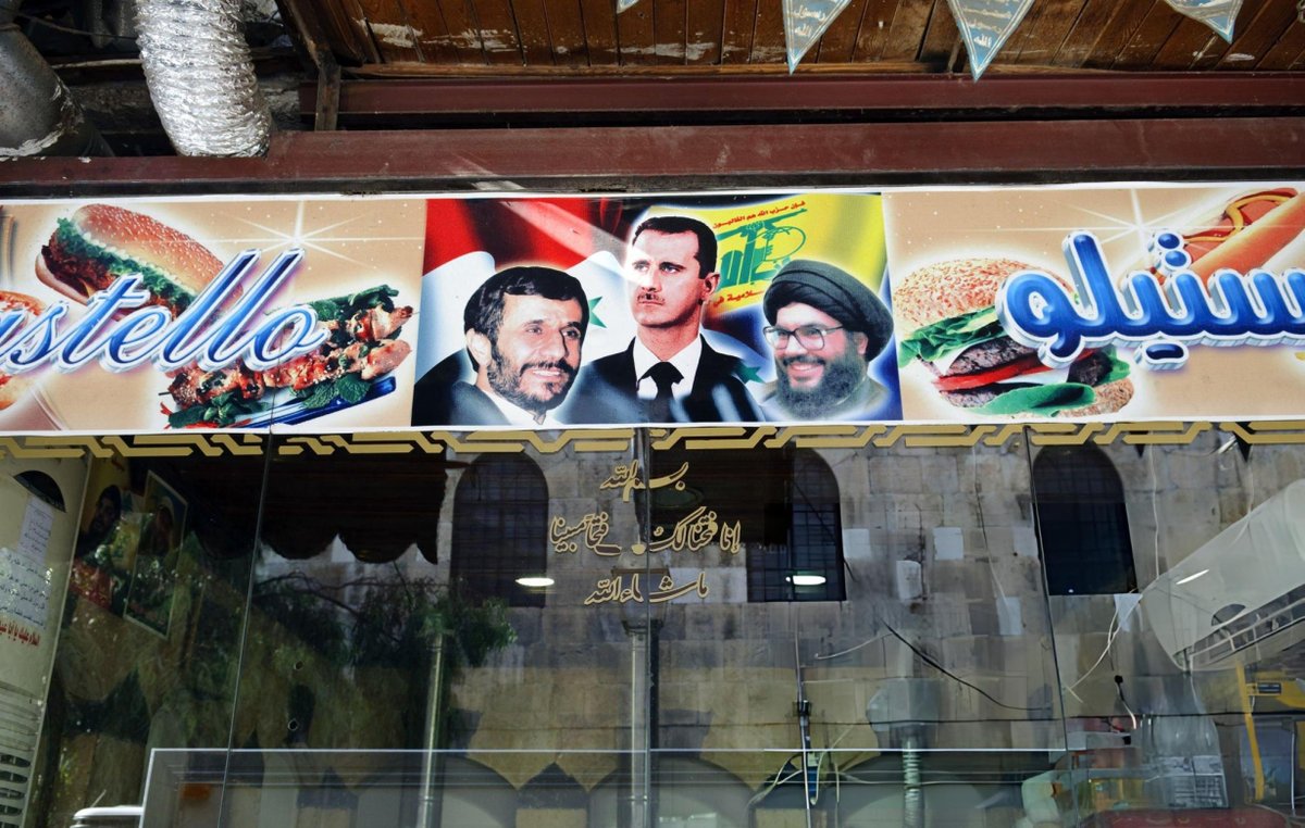 BaathistSyria's tweet photo. A poster featuring portraits of Mahmoud Ahmadinejad, Bashar al-Assad and Hassan Nasrallah on the outside wall of a restaurant in Damascus, 2010 https://t.co/kvizlbUXB5