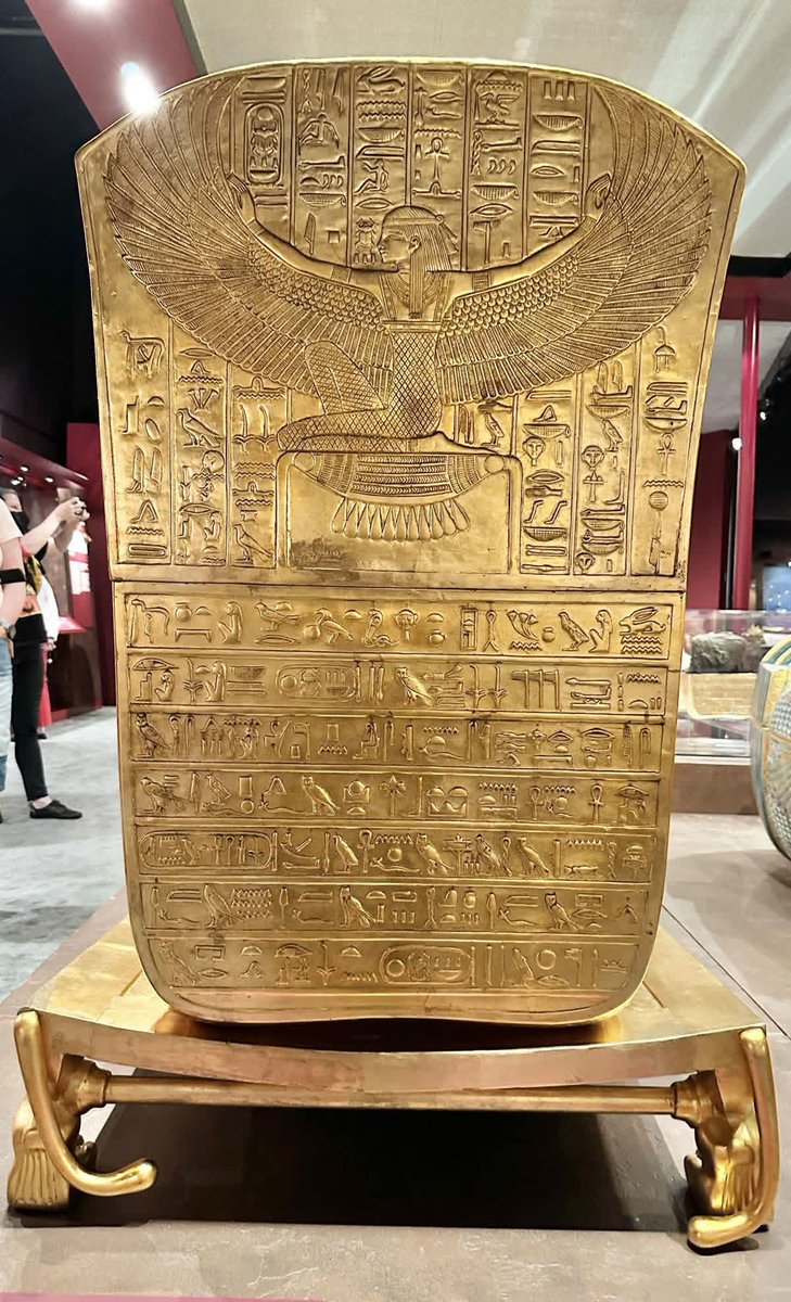 Displayed today within a museum setting, this gilded funerary stele originates from ancient Egypt and dates to the Late Period or early Ptolemaic era (c. 7th–3rd century BCE). Fashioned from hammered gold, its surface is densely engraved with hieroglyphic texts and sacred