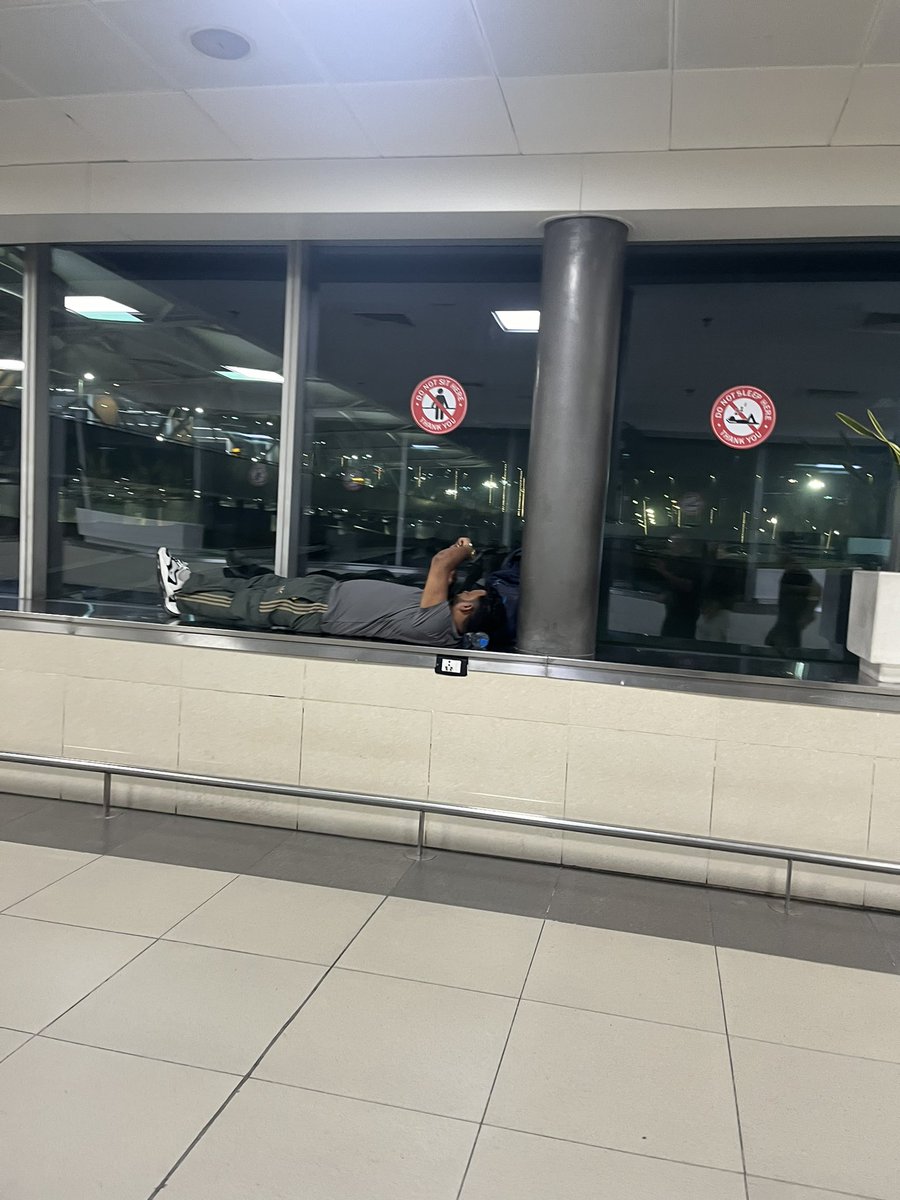 probingtweeter's tweet photo. @DelhiAirport @AAI_Official only at T3 ppl keep sleeping in the corridors and open spaces, like a railway station. Right under the signs that prohibit it https://t.co/0St33zuue4