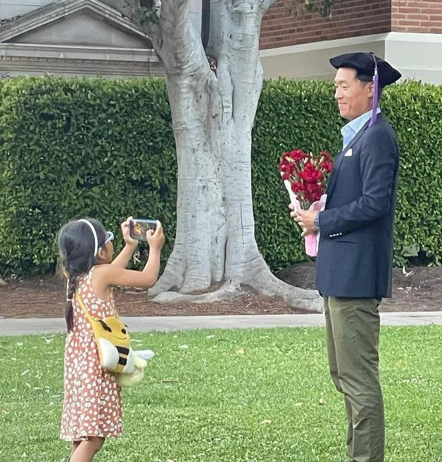 23. Una niña pequeña tomando fotos de su papá que acaba de graduarse. Solo eran ellos dos.