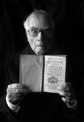 En Joan Perucho amb cara d’espant mentre subjecta un llibre sobre aparicions d’esperits i vampirs