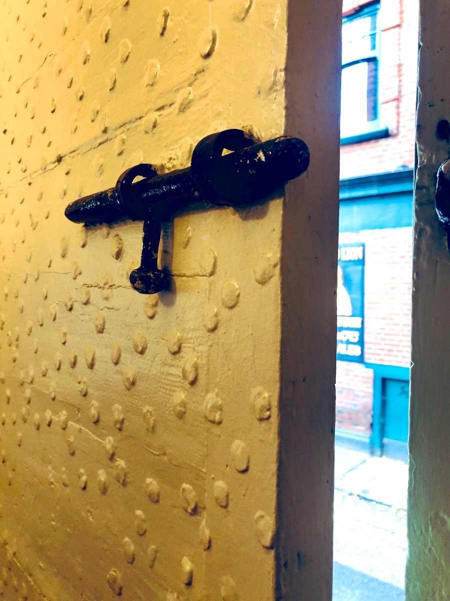 HistoryOfStokey's tweet photo. According to architect Darren Silk, the front door of 130 Stoke Newington Church St is original from the 1720s, making it one of the oldest if not the oldest residential front door in Stoke Newington potentially.

I’ve been wondering what all the dots on the door were. Turns out they are nails/studs. Here’s Darren’s explanation: “The planks in the inner with the nails all across the face is an old technique to prevent axes from cutting into it. Derived from castles. 

Usually spiked on the exterior, but in this instance likely to both hold the planks on for reinforcement, and to catch anything trying to get though. Nails get axes jammed as they get caught between the nails, and these are facing outwards, so if someone managed to get though what looked like a conventional door they'd be faced with sharp nail ends. I can only imagine how bad that would have been in the age before tetanus injections”