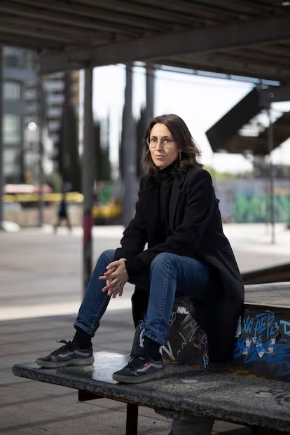 L’Eva Baltasar asseguda com la jovenalla en un banc a prop de l’estació de Sants