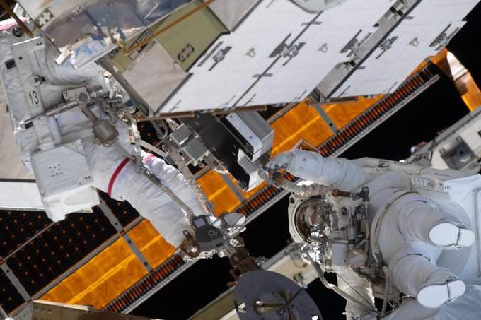 Two NASA astronauts, Jessica Meir (left) and Christina Koch (right), work outside of the International Space Station during a spacewalk. They are both wearing white spacesuits. Credit: NASA/Drew Morgan