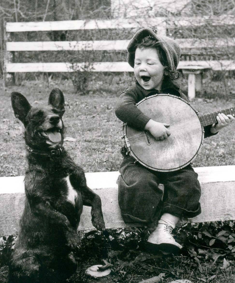 24. Niña tocando el banjo para su perro, alrededor de 1934.