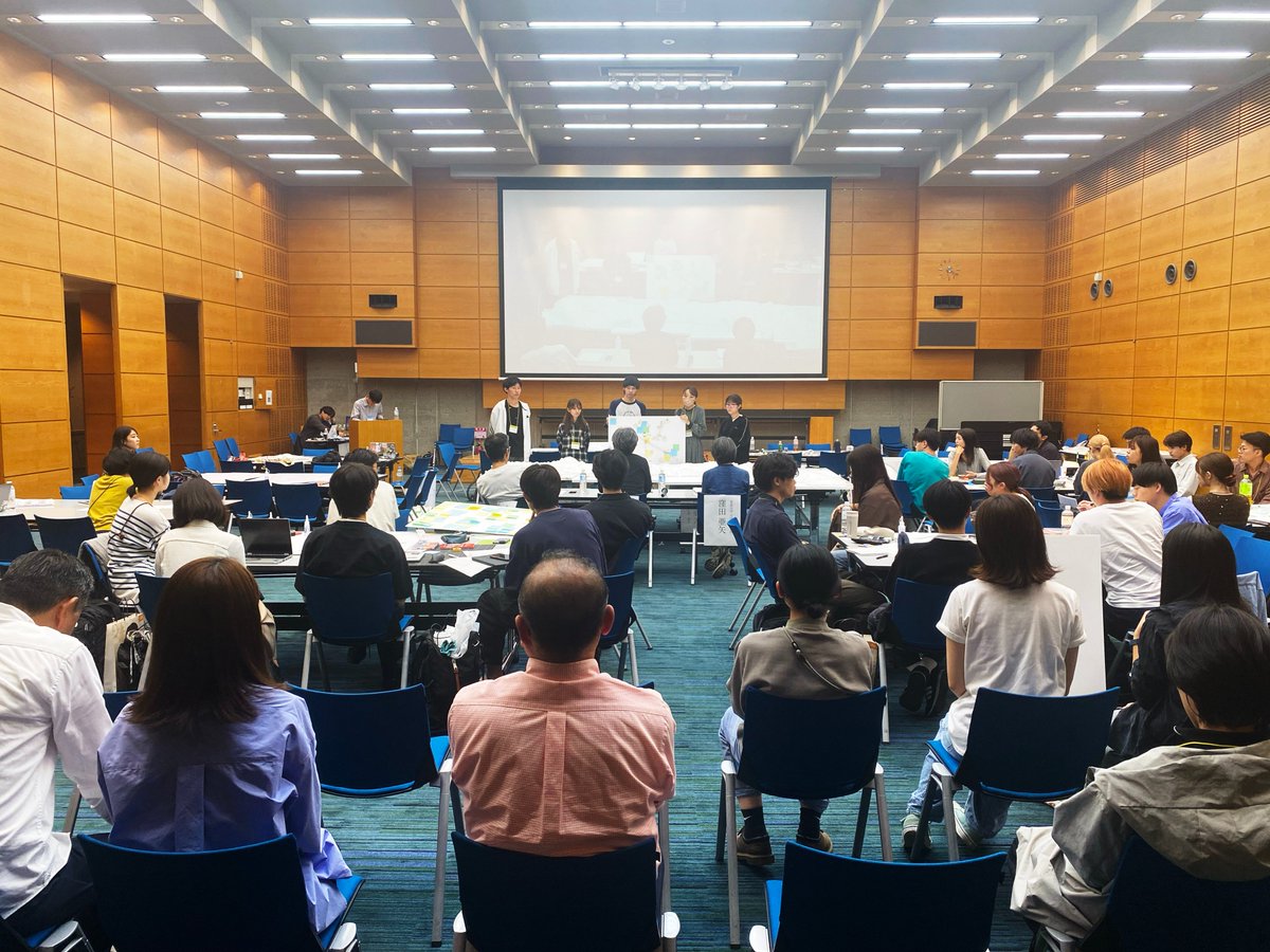 tatsumatsuda's tweet photo. 建築会館ホールでの #学生WS2024 中間発表。中庭には岡田翔大郎さんのちびでか山が設置されており、七尾の青柏祭の曳山行事の音が風とともにうっすらと聞こえてくる。ここで能登に対して学生に何が出来るのか？大学混交の各チームが提案。プロジェクト概要書、関係図・ステークホルダーマップを提示。 https://t.co/jvTKM5Mnvb