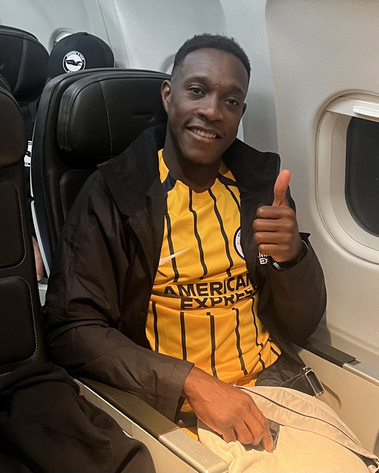 Danny Welbeck gives a thumbs up on the flight home from Newcastle. Danny is wearing our yellow away kit and a black Albion jacket.