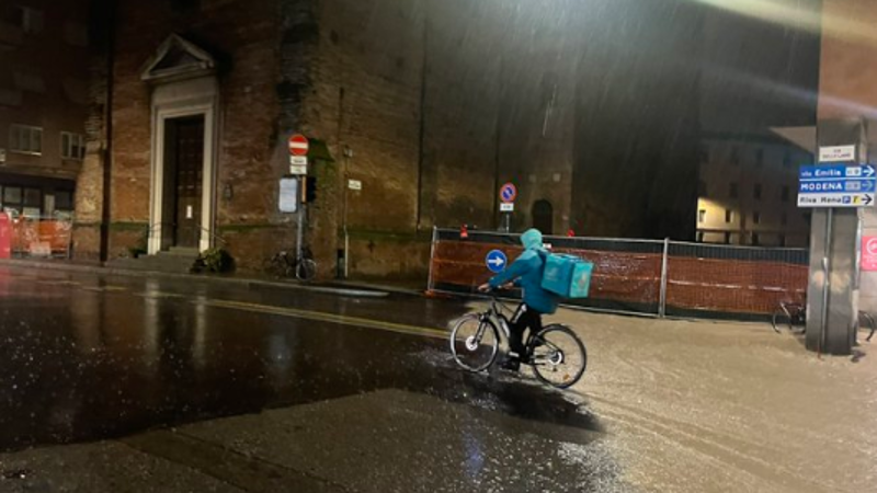 Il capitalismo nell'Antropocene: i rider a Bologna che lavorano durante la quarta alluvione che colpisce la regione Emilia-Romagna in un anno - alluvioni rese più frequenti e più gravi del cambiamento climatico causato dall'attività umana.