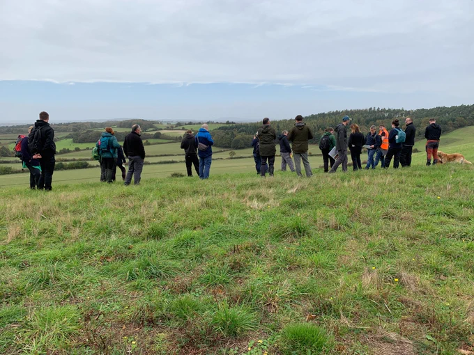 Group of people in a field, learning about the National Trust’s work to restore heathland mosaics